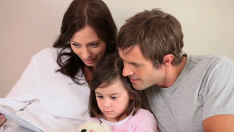 familia sonriente leyendo un libro en voz alta