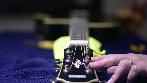 encordando y limpiando una hermosa guitarra acústica negra con un solo cutaway: el encordado está completo, así que le damos a la guitarra un pulido final con un plumero