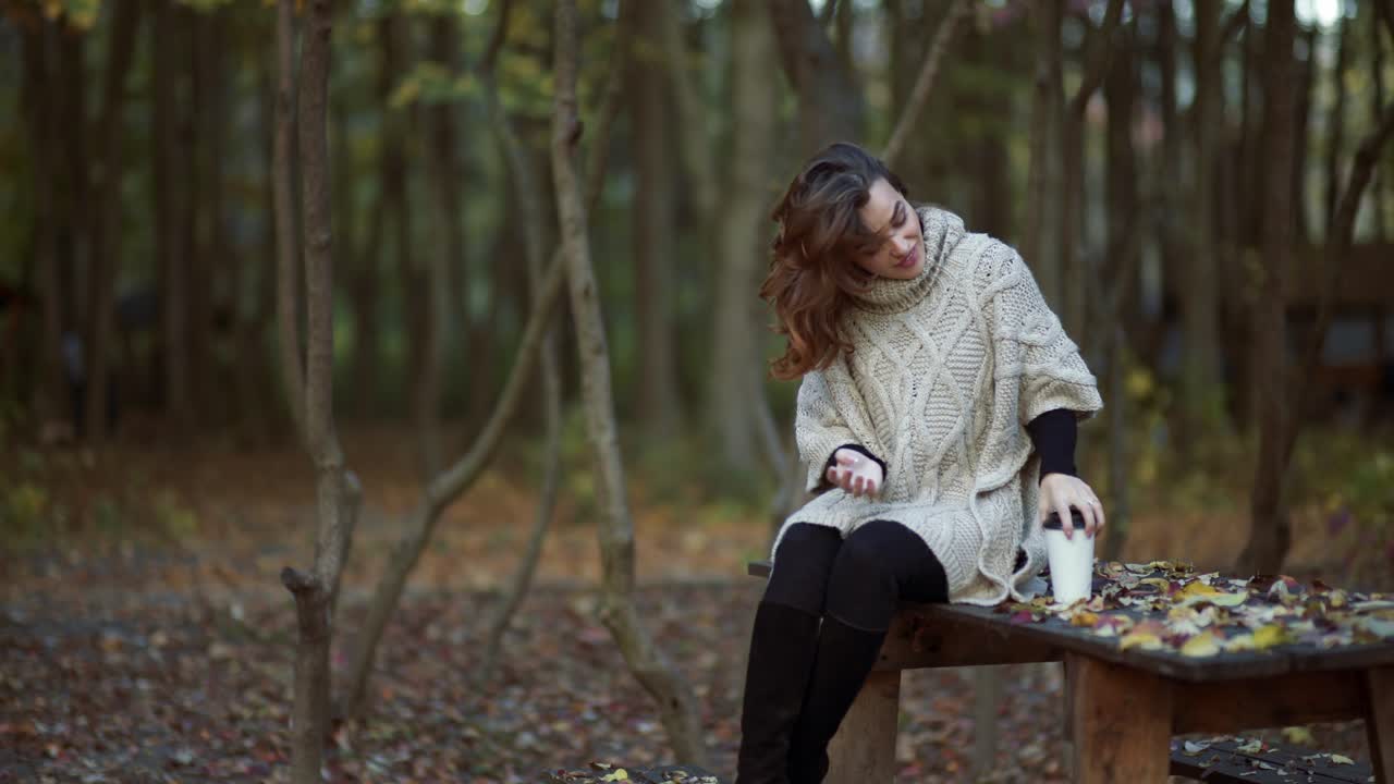 Woman spending time in park. Young woman spending time with cup of coffee in autumn park