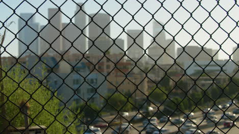 los angeles moving traffic view through a grilled fence with skycrapers in the background