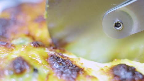 close up shot of a pizza cutter cutting delicious tasty home made gourmet pizza