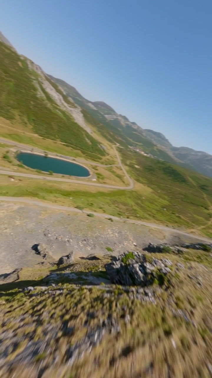 Video verticale dinamico di drone FPV che si libra sopra i pendii scoscesi di Puerto San Isidro nella Cordigliera Cantabrica, Asturie, Spagna, sotto un cielo azzurro e limpido. Scatto montano incontaminato