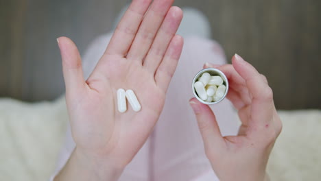 persona que sostiene pastillas y un recipiente de pastillas