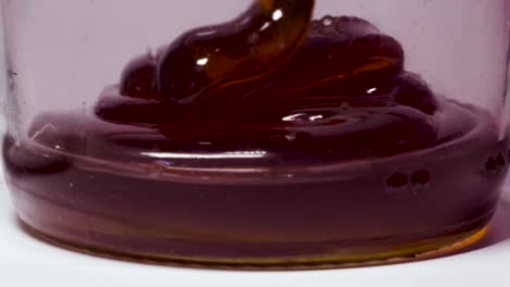 Thick-drizzles-of-honey-pouring-into-glass-mason-jar,-Closeup-Texture