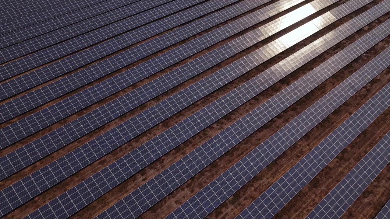 Omfattende luftoptagelser over geometriske rækker af solpaneler på en solbeskinnet italiensk solcellepark om sommeren, der fanger ren energiteknologi og dynamisk komposition set ovenfra i gyldent lys