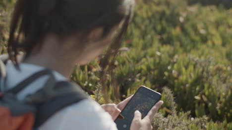 primer plano de una chica con mochila tomando una foto de una flor inusual