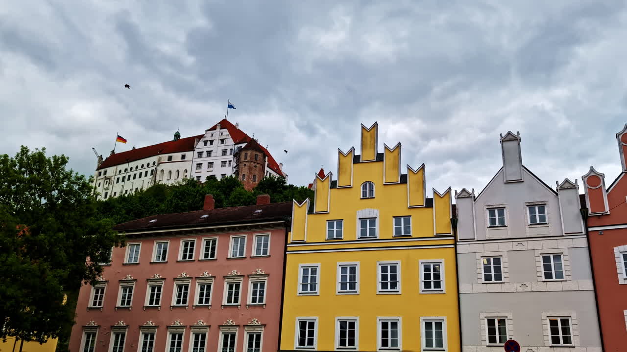 Trausnitz Castle rising above colorful Landshut townhouses under cloudy sky