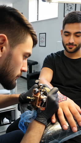 Tattoo artist working on a client&#039;s arm