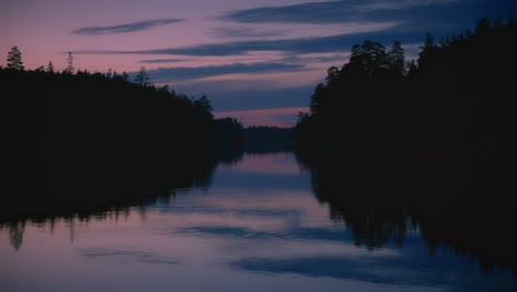 magical sunset reflection in swedish lake with dark forest silhouette