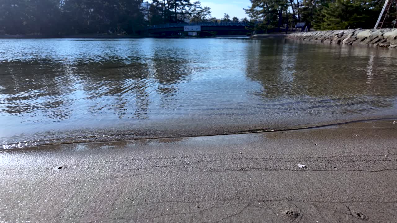 Calm sea waves gently lapping the sandy shore of Amanohashidate sandbar, creating a serene and peaceful atmosphere