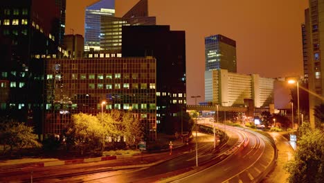 from a high vantage point, a timelapse captures the busy, bustling essence of a city at night with a highway threading its way through lit-up, modern skyscrapers