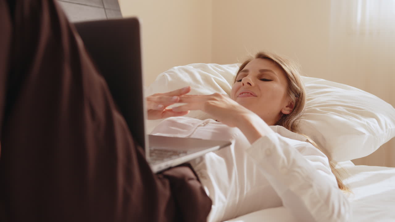 침대에 노트북으로 일하는 여자