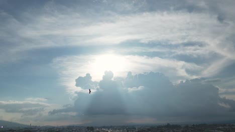 Drohnenaufnahme-Von-Sonnenstrahlen,-Die-Durch-Große-Wolken-Kommen,-Mit-Fliegenden-Vögeln-Im-Vordergrund