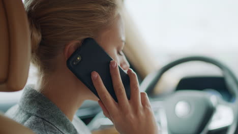 vista traseira de mulher falando ao telefone no carro. mulher apoiada no volante do carro