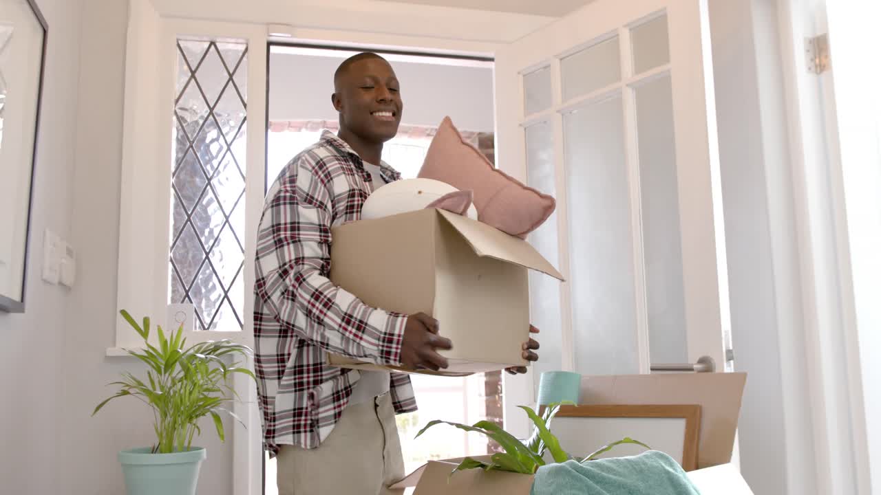 feliz hombre afroamericano llevando cajas en casa, cámara lenta