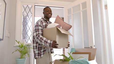 Happy-african-american-man-carrying-boxes-at-home,-slow-motion