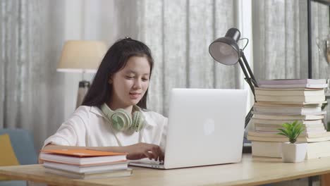 teenage girl studying on laptop at home