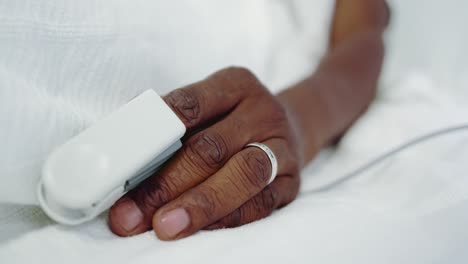 Close-up-of-pulse-oximetry-on-African-american-male-patient-hand-in-the-ward-at-hospital