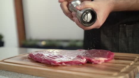 primer plano de un chef agregando pimienta a un bistec de carne cruda, cámara lenta
