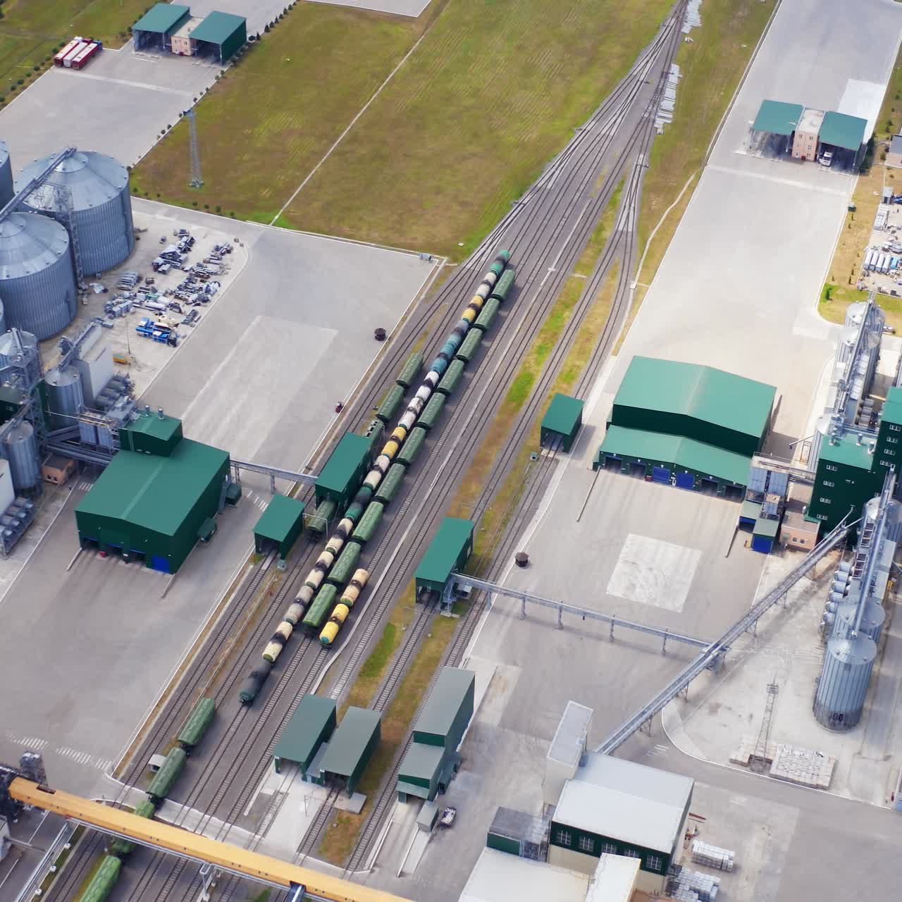 Modern agricultural manufacture on field. Grain elevators for storing cereals on a large plant. Cargo trains on industrial territory. Aerial view
