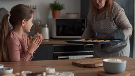 Grandmother-and-granddaughter-taking-ready-cookies-out-of-the-oven.