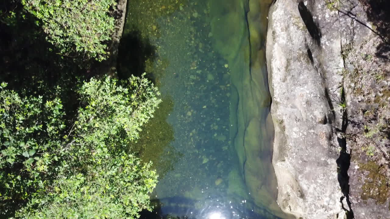 드론은 맑고 투명한 호주산 개울 위를 천천히 날아 물을 내려다보며 개울 바닥에 있는 바위, 자갈, 모래를 보여줍니다.