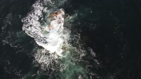 Vista-Aérea-De-Una-Formación-Rocosa-Con-Olas-Oceánicas-Golpeando-Y-Salpicando-Pilas-De-Mar-En-La-Playa-De-Canto,-Estados-Unidos