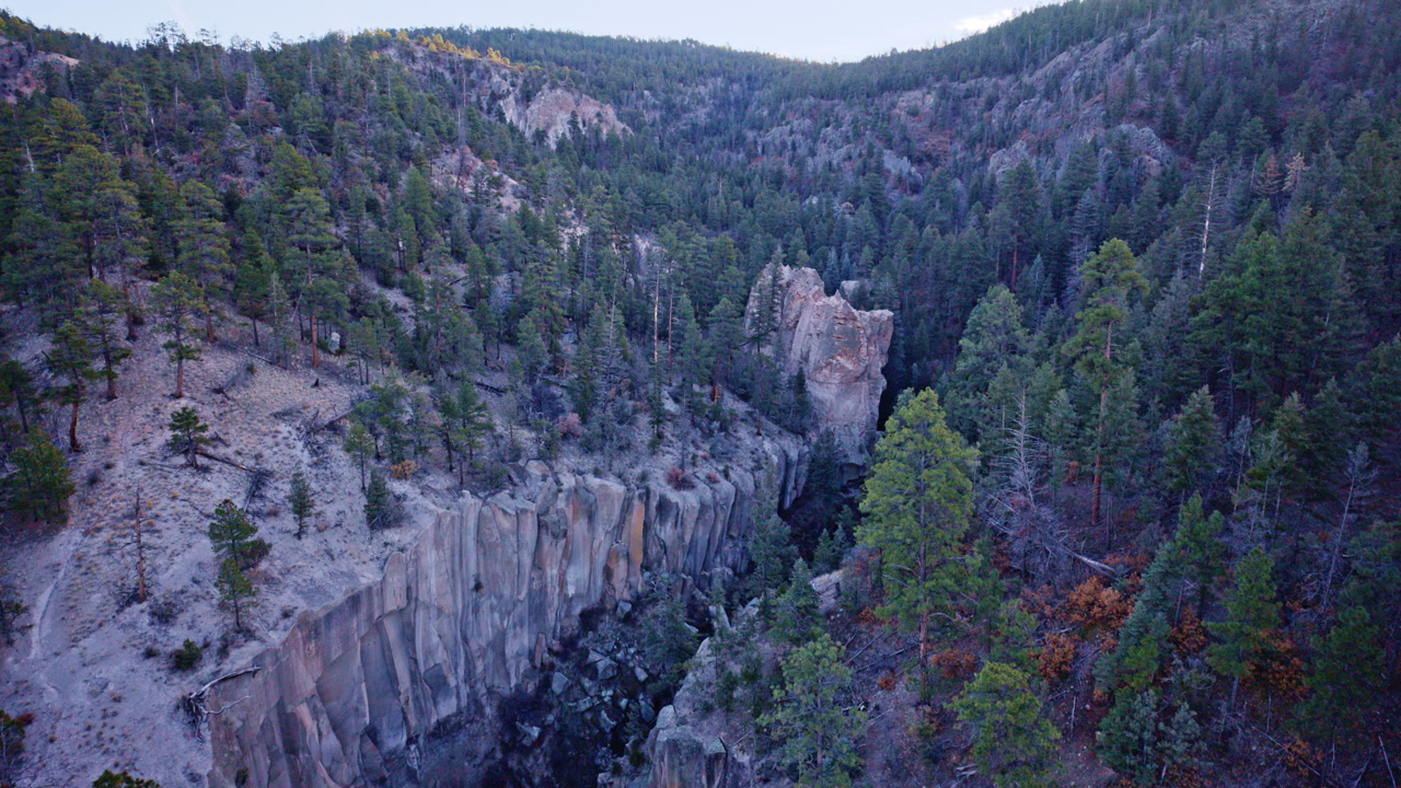Cinematic aerial view of canyon terrain and rocky cliffs near Los Alamos NM