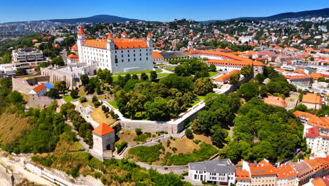 approaching the territory of bratislava castle surrounded by the green gardens. landmark of slovakia from aerial view