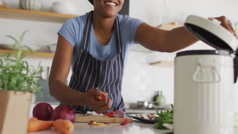 Happy-african-american-woman-cleaning-waste-in-kitchen