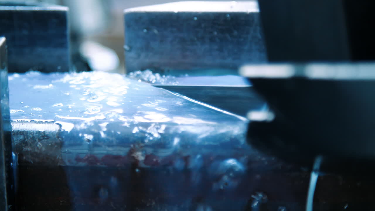 Coolant splashes fall on surface of metal during sawing on metalworking machine