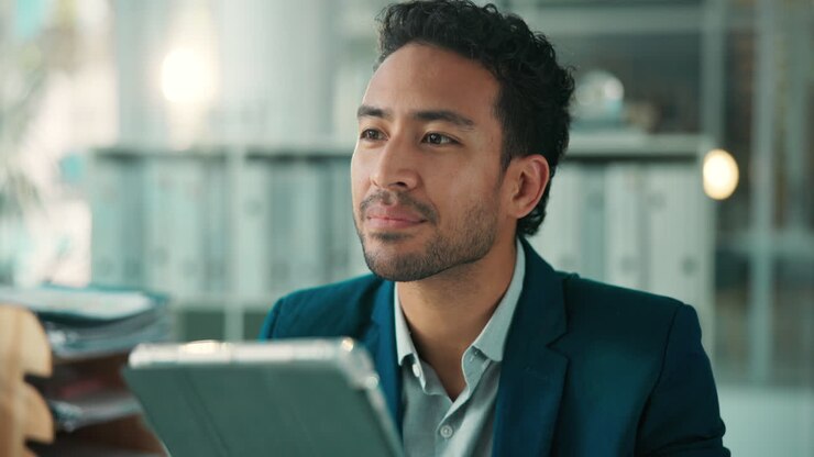 Professional Man Working and Smiling While Using a Digital Tablet in Office