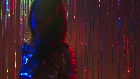 portrait of woman having fun in nightclub or bar dancing against sparkling tinsel curtain in background 1