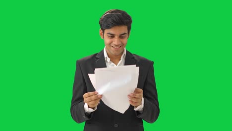 un hombre de negocios indio feliz leyendo el contrato en pantalla verde.