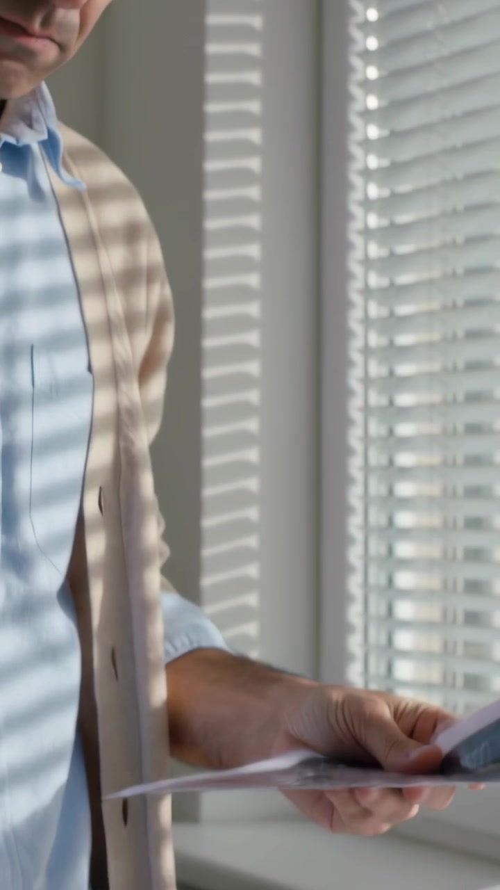 Vertical video: Checking man cardigan, glasses holding grid by blinds, sorting pile, copy space