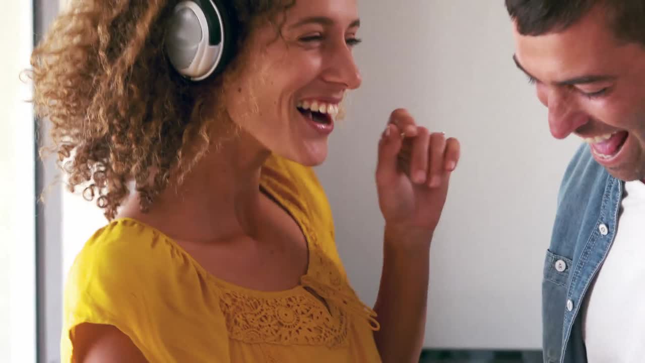 pareja linda escuchando música con auriculares y bailando