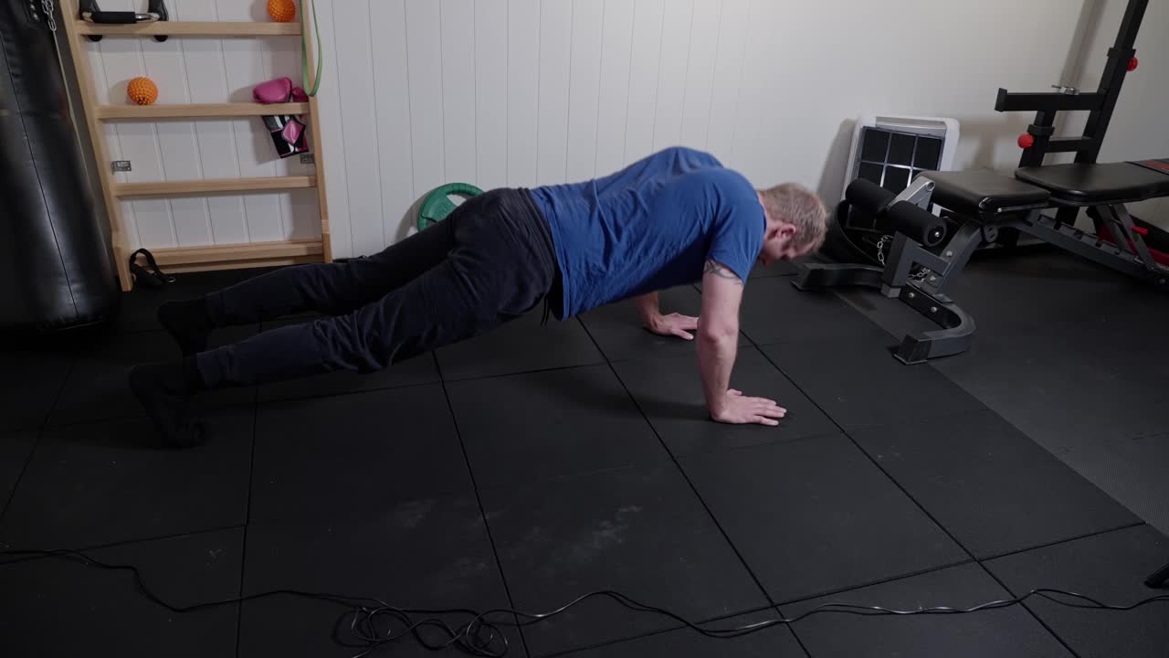 hombre de mediana edad haciendo flexiones en su gimnasio en casa