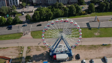 Ferris-wheel-operating-at-busy-multi-lane-road.-Descending-and-tilt-up-reveal-of-housing-estate-in-city