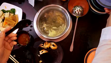 woman throws seashells and prawns into boiling broth