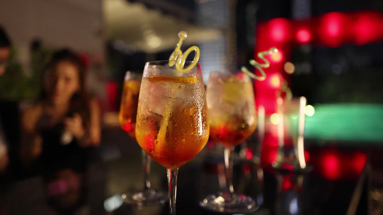 A lively scene with cocktails and friends in a warmly lit, festive environment. Focus on drinks and social interaction