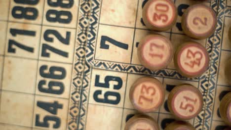 cinematic close-up smooth rotating shot from above of bingo wooden barrels in a row, woody figures, old numbers background, vintage board game, slow motion 120 fps commercial gimbal video