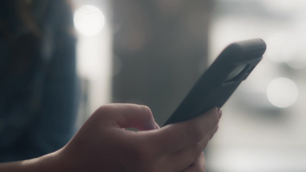 Primo piano di una donna che scorre il suo smartphone mentre aspetta al gate.