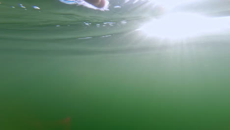 pov shot, male swimmimng underwater with air bubbles and light rays, slowmotion