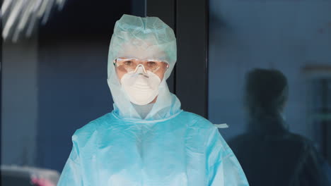 doctor in protective suit and mask shows stop hand sign