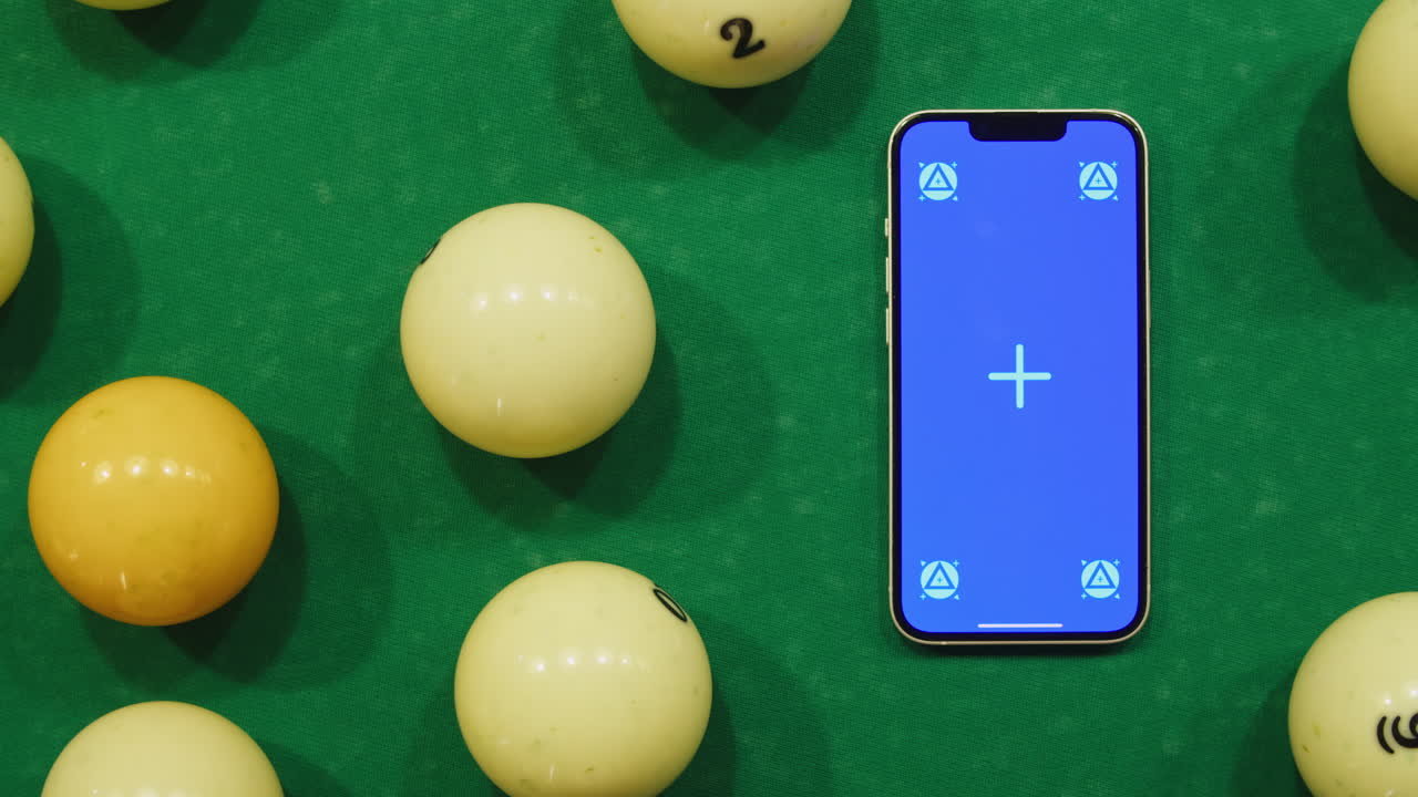 Telefono con chroma key su un tavolo da biliardo verde tra palle colorate. Partita di biliardo. Smartphone con schermo verde. Filmato 4k di alta qualità