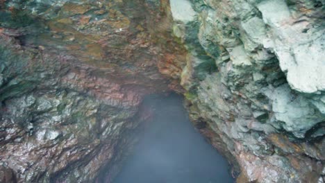 HD-Hawaii-Kauai-Bootfahren-Auf-Dem-Meer,-Das-Entlang-Der-Höhlenwand-Des-Ozeans-Schwimmt-Und-Aus-Der-Höhle-Herausschwebt,-Um-Einen-Wasserfall-Freizulegen,-Der-Ins-Meer-Fällt