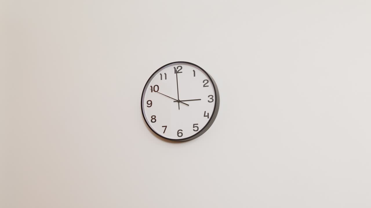 A black and white wall clock with a professional, corporate look, mounted on a plain white surface and showing 3:00.
