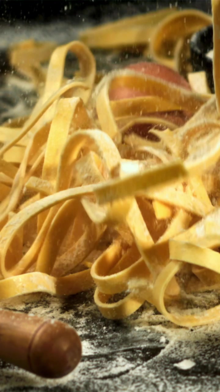 Pasta fresca che cade al rallentatore su una superficie infarinata
