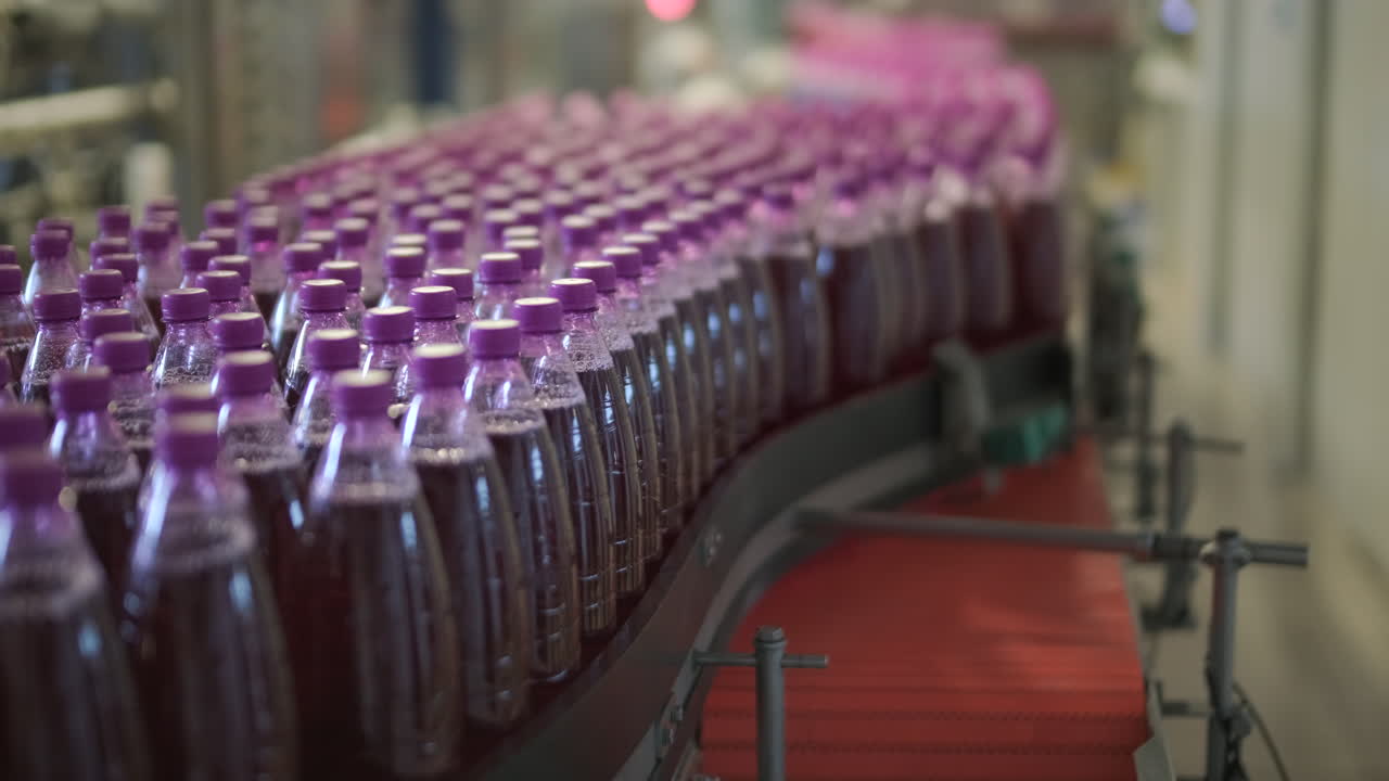 Garrafas de bebidas se movendo em uma esteira transportadora em uma fábrica
