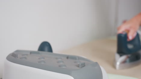garment maker takes iron, places on apparel, steam rising, ensuring neat finish, focusing on proper pressing technique, demonstrating professional approach, achieving smooth fabric outcome